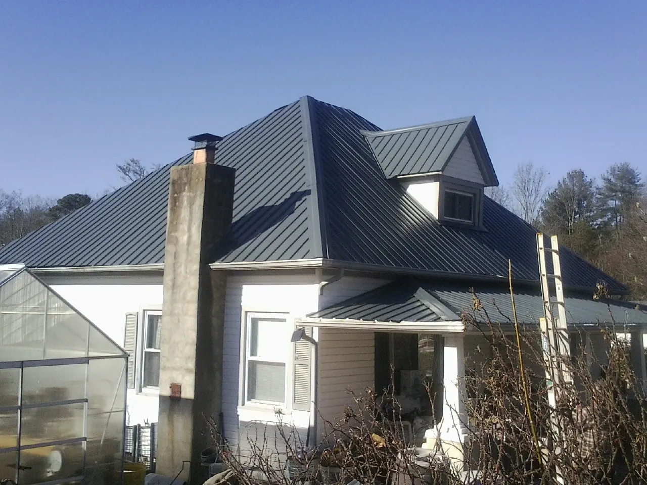 Dark blue standing seam metal roof on a white farmhouse with dormer — Slate & Tile Roof Repair by Roofing Brothers in Mifflintown