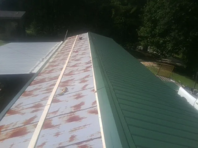 Old rusted panels beside newly installed green metal roofing — Wind Damage Roof Repair by Roofing Brothers in Mifflintown