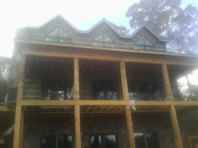 Dormers and porch framing on a large log home under construction — Roof Coating work by our crew in Mifflintown