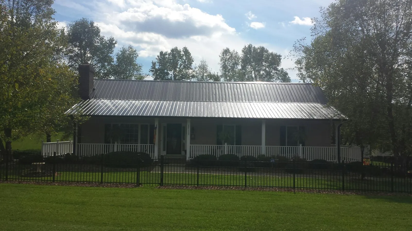 Gray metal roof on a brick ranch with a full width front porch — Gutter Guard Installation work by our crew in Mifflintown