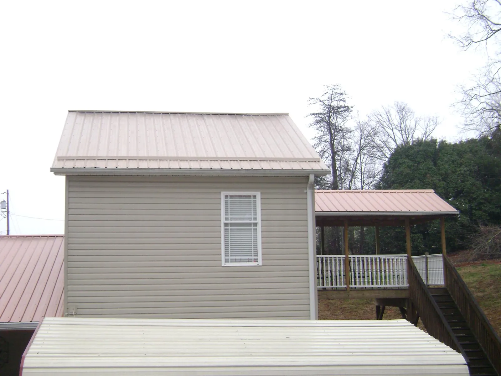 Tan metal roofs on a two story addition and attached porch, from a Roof Replacement job in Mifflintown