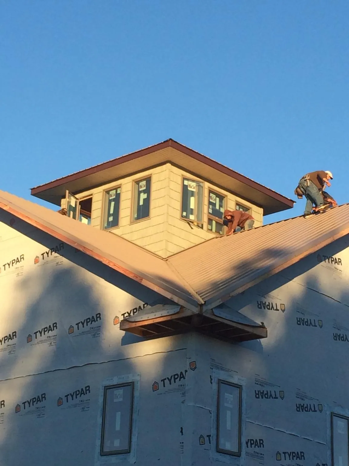Roofers working around a rooftop cupola on a new metal roof at sunset — Roof Waterproofing in Mifflintown by Roofing Brothers